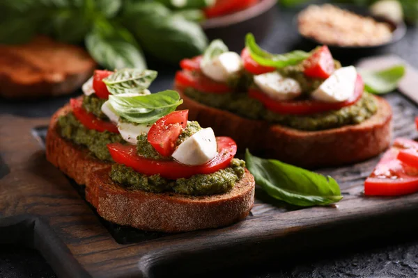 İtalyan mutfağı. Taşralı. Pesto sosu, taze domates, mozzarella ve fesleğen ile ahşap bir tahtada siyah bir masa. Arkaplan resmi, alanı kopyala. 