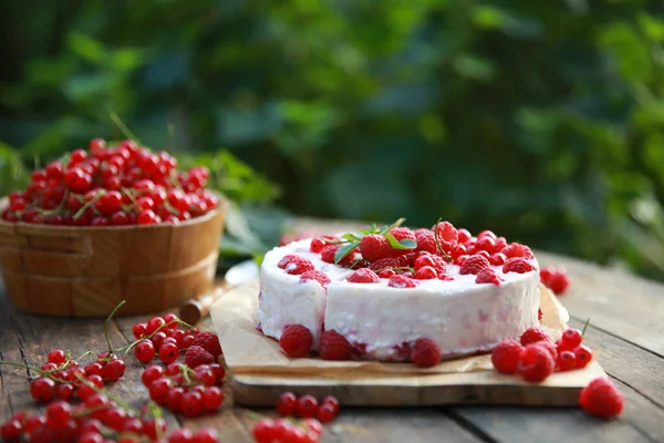 Summer atmosphere. Russian cuisine. Dacha, nature. Cottage cheese pie, cake with fresh berries: red currants and raspberries on an old wooden table. Background image, copy space