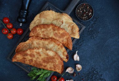 Ulusal yemek Tatar mutfağıdır. Tahtada Chebureks var. Kıyma, ot, domates, baharat ve sarımsaklı hamur. Arkaplan resmi, alanı kopyala