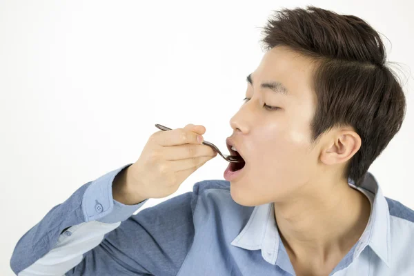 Ασιατική άνθρωπο τρώνε κάτι με πιρούνι πλαστικό — Φωτογραφία Αρχείου
