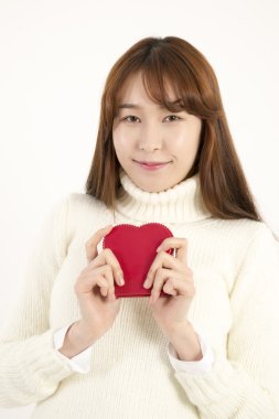 Gülümseyen genç Asyalı kadın kırmızı kalp şeklinde