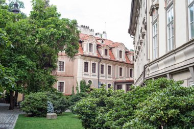 Prag, Çek Cumhuriyeti, Avrupa 'daki eski evlerin bahçesindeki çimenlikte oturan bir kızın heykeli olan yeşil bahçe. Yeşillikteki evler.