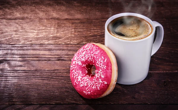 White mug of coffee and a donut on a wooden background — Stock Photo, Image
