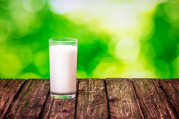 Ποτήρι γάλα σε ένα ξύλινο τραπέζι φύση θαμπάδα — Φωτογραφία Αρχείου