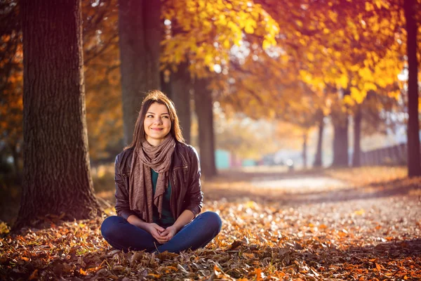 Jente som sitter i parken høst – stockfoto