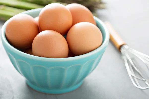 Свежие яйца в миске с венчиком — стоковое фото