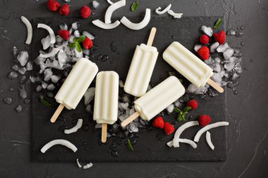 Siyah arka plan üzerine ahududu ile Hindistan cevizi popsicles