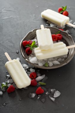 Siyah arka plan üzerine ahududu ile Hindistan cevizi popsicles
