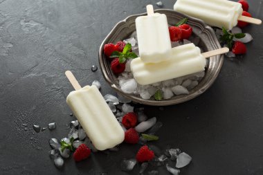 Siyah arka plan üzerine ahududu ile Hindistan cevizi popsicles