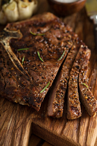 Tbone beef steak cooked on a grill with rosemary and garlic