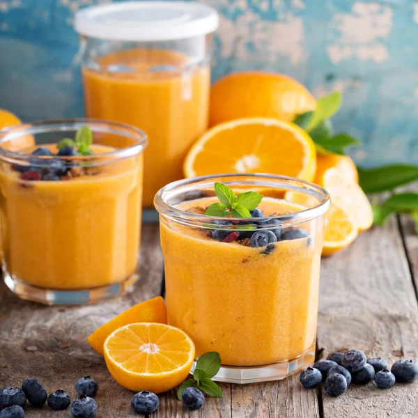 Oranje en mango smoothie met muesli en bessen — Stockfoto