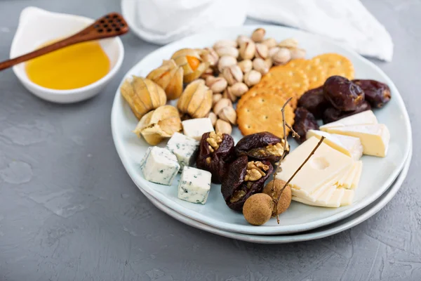 Cheese plate with crackers, dates and nuts — Stock Photo, Image