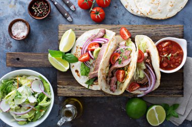 Biftek tacos dilimlenmiş karşılamak, salata ve domates salsa ile
