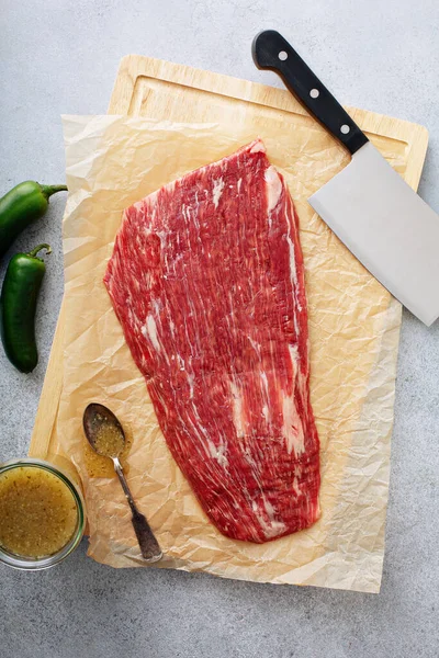 Raw flank steak on a cutting board