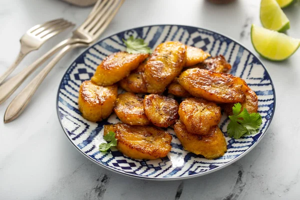 Fried caramelized plantains served with lime wedges — Stock Photo, Image