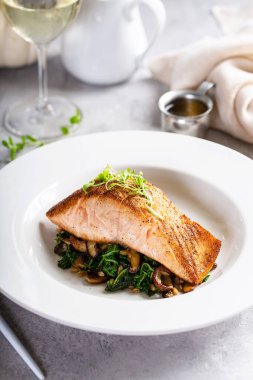 Sotelenmiş sebze ve mantarla servis edilen somon filetosu.