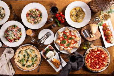 İtalyan yemekleri, pizzalar ve pizzalarla dolu büyük bir yemek masası.