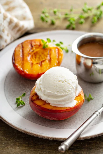 Grilled peaches with ice cream and caramel sauce, summer dessert