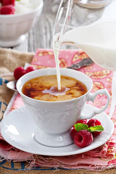 Cup of tea with milk pouring over — Stock Photo, Image