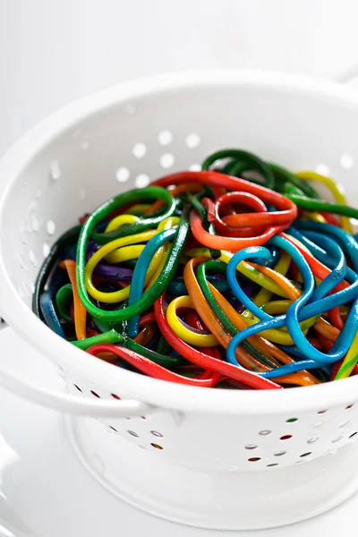 Rainbow colored spaghetti in a colander — Stock Photo, Image