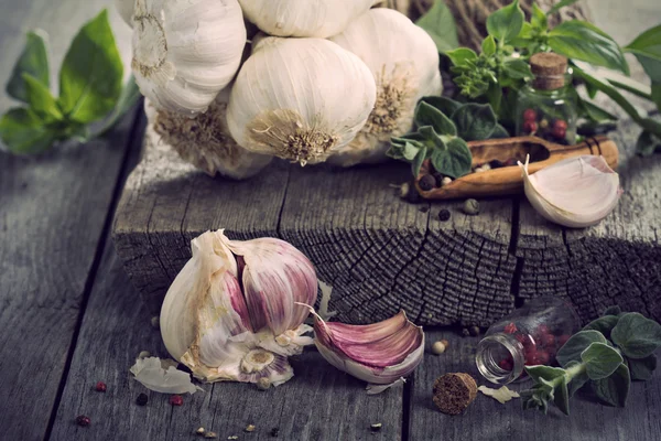 Färsk vitlök, kryddor och sallad lämnar på bord — Stockfoto