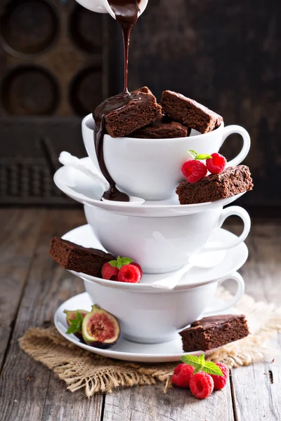 Brownies dans des tasses à café empilées avec sauce au chocolat Photo De Stock