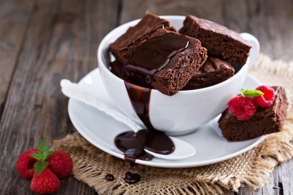 Brownies dans des tasses à café empilées avec sauce au chocolat Images De Stock Libres De Droits