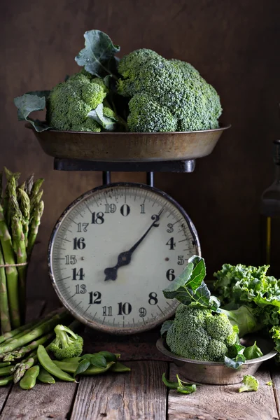 Fresh green vegetables on old kitchen scales