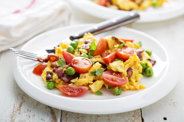 Scrambled eggs with peas, bacon and tomatoes — Stock Photo, Image