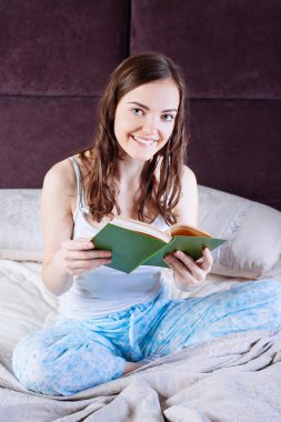 kitap okurken yatakta yatan kadın