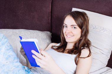 kitap okurken yatakta yatan kadın