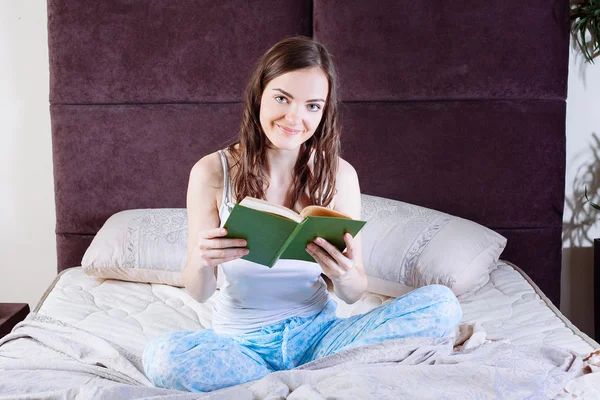 Женщина лежит в постели, читая книгу — стоковое фото