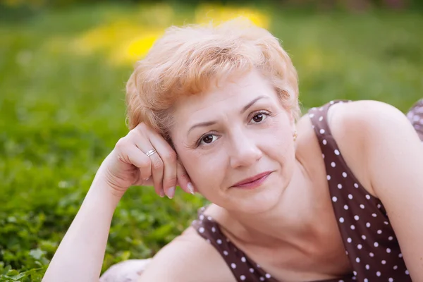 Portrait of middle aged woman smiling in the park — Stock Photo, Image