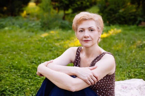 Porträt einer Frau mittleren Alters, die im Park lächelt — Stockfoto