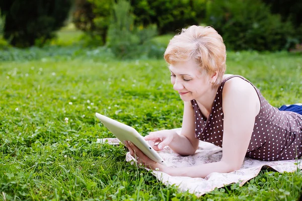 Porträtt av mellersta äldre kvinna med hjälp av Tablet PC i parken — Stockfoto