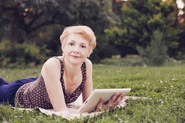 Retrato de mujer de mediana edad usando tableta en el parque — Foto de Stock