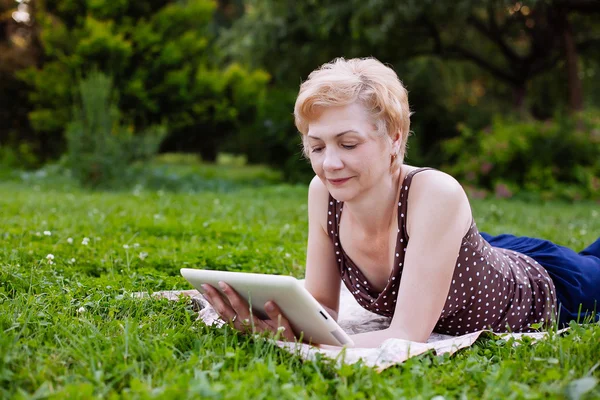 Retrato de mujer de mediana edad usando tableta en el parque — Foto de Stock