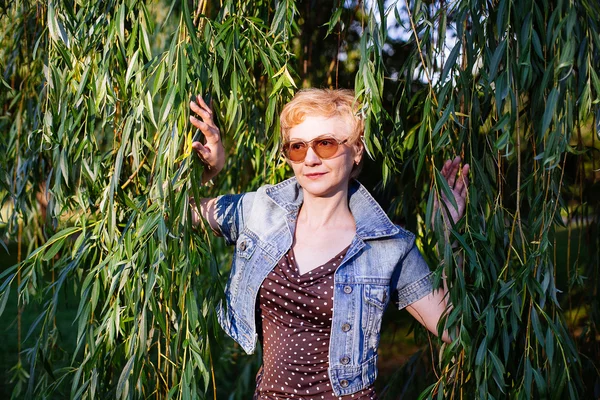 Portret van stijlvolle midden leeftijd vrouw die lacht op de natuur bac — Stockfoto