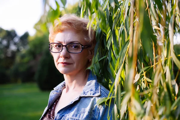 Retrato de mujer de mediana edad con estilo sonriendo en la naturaleza bac —  Fotos de Stock