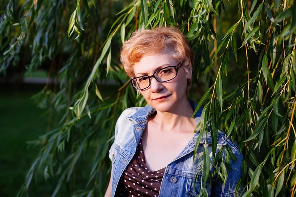 Portrait de femme d'âge moyen élégant souriant sur la nature bac — Photo