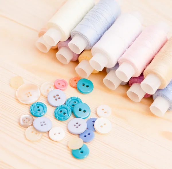 Threads and buttons  on wooden table — Stock Photo, Image