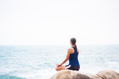 Deniz kaya üzerinde Lotus olarak oturan kadın bir