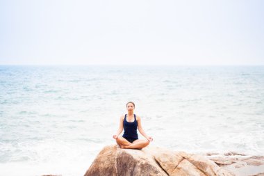 Deniz kaya üzerinde Lotus olarak oturan kadın bir