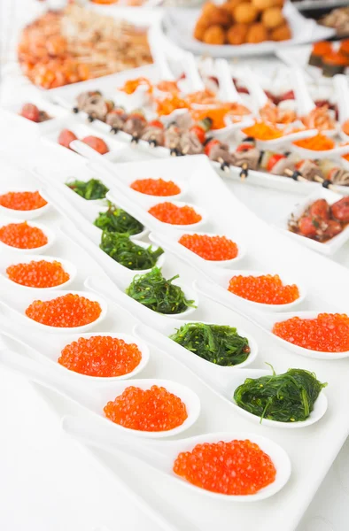 Caviar rouge en gros plan dans des cuillères blanches sur le banquet — Photo