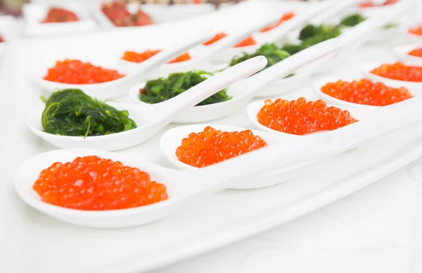 Caviar rouge en gros plan dans des cuillères blanches sur le banquet — Photo