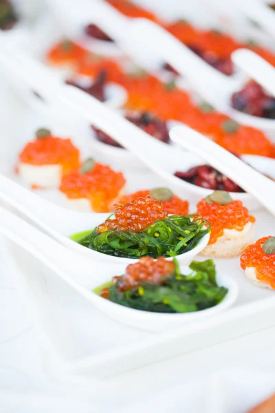 Red caviar close-up in white spoons on banquet — Stock Photo, Image