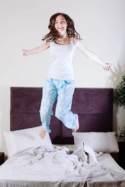 Mutlu genç bir kadın yatakta atlama — Stok fotoğraf