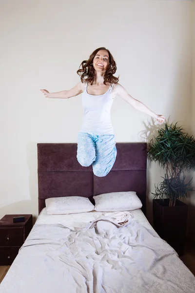 Счастливая молодая женщина, прыгающая на кровати — стоковое фото