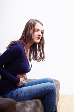  Genç kadın oturup üzerinde kanepe acı gelen mide ağrısı