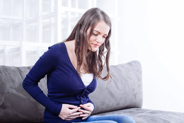 Young Woman Sitting On Sofa Suffering From stomach ache — Stock Photo, Image